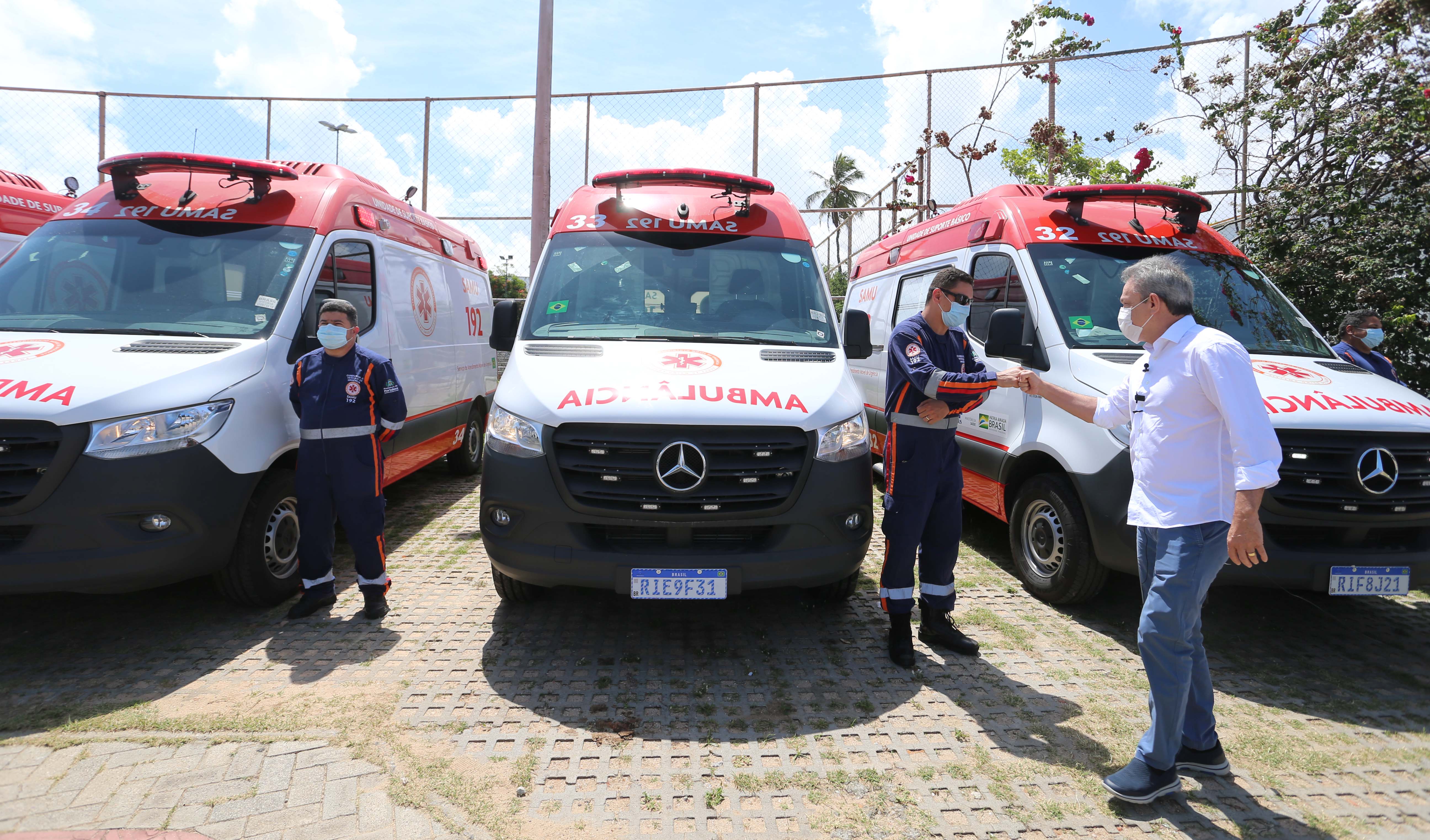 sarto cumprimenta, à distância, um profissional do SAMU que está na frente de uma ambulância do serviço